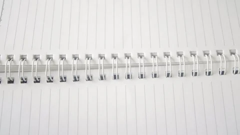 This video shows a notebook with blank lined pages being flipped, some page.. Stock Footage 332913914