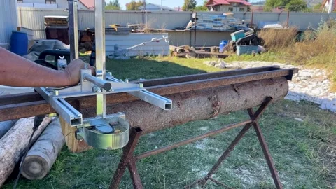 Video shows person using portable chainsaw mill attachment on large raw log Stock Footage 326036772