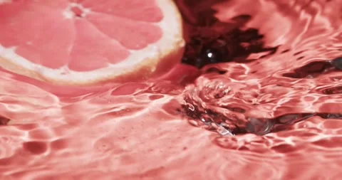 Video of slice of red grapefruit falling into water with copy space on red Stock Footage 331295169