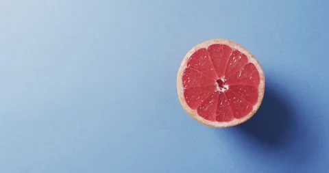 Video of sliced red grapefruit with copy space over blue background Stock Footage 331307235