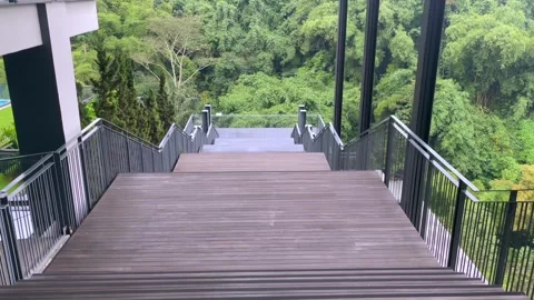 Video slow motion walking down wooden stairs towards green forest scenery Stock Footage 324751069
