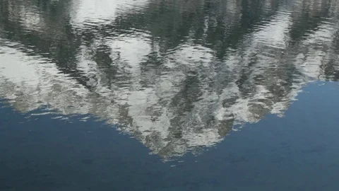 A video of a snow capped mountain reflecting in a calm lake.  Vídeo Stock 72435847