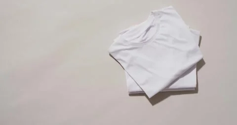 Video of stack of folded white t shirts with copy space on white background Stock Footage 247354248