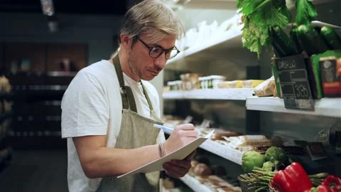 Video of store owner arranging vegetables in rack at organic market Stock Footage 201823568