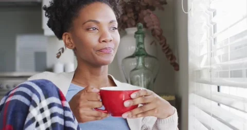 Video of thoughtful african american woman drinking coffee and looking outside Stock Footage