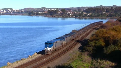 Video of train running along mountains and lake. Video stock 207382870