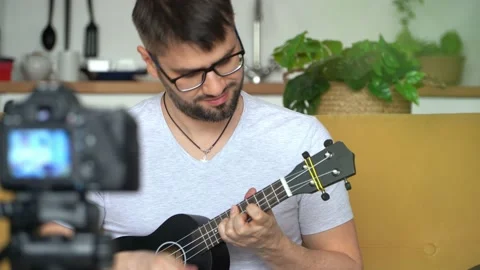Video tutorial, online music training. Young blogger playing guitar at home Vídeo Stock 154232632