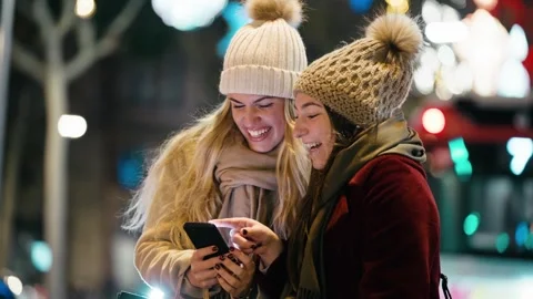 Video of two beautiful friends using smartphone while walking on the city s.. Stock Footage 340825441