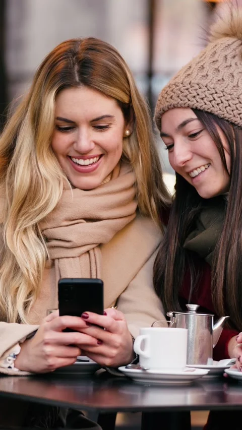 Video of two beautiful women using smartphone while drinking coffee sitting.. Stock Footage 340825484
