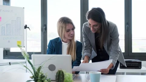 Video of two business young women reviewing papers of work with laptop in the Stock Footage