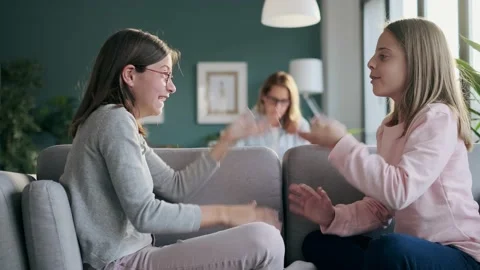 Video of two cute sisters playing hands game while sitting in couch in the li Stock Footage 157024418