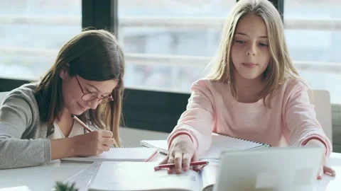 Video of two cute sisters using digital tablet while doing homework in living Stock Footage 157024445