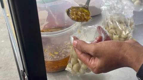 Video vendor adding chili powder, garlic oil, and salt to cimol street food. Stock Footage 321554092