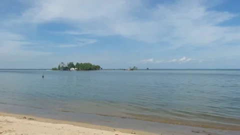 Video of a view of the beach with a small island in the middle during the day Stock Footage 324355728