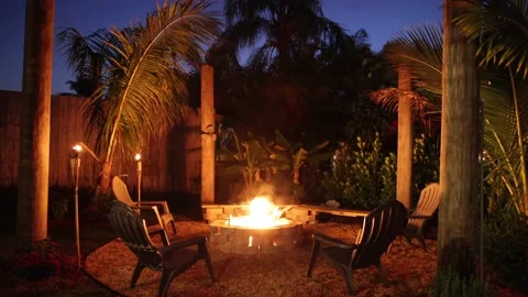 This is a video walking toward tropical backyard firepit with tiki torches. Stock Footage 153453079