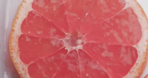 Video of water drops falling onto slice of red grapefruit with copy space on Stock Footage 331447692