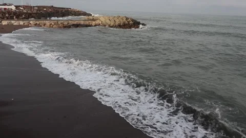 Video of waves reaching a sandy beach with a coastal town view. Stock Footage 323002731