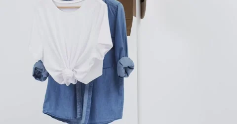 Video of white and denim t shirt on hangers, hat and copy space on white Vídeo Stock 331208542