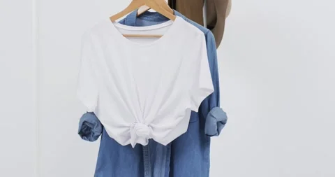 Video of white and denim t shirt on hangers, hat and copy space on white Vídeo Stock 331208543