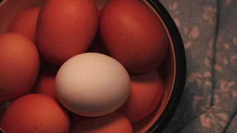 Video of a white egg surrounded by brown eggs in a bowl. Food concept. Stock Footage 262804792