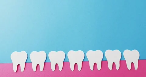 Video of white paper teeth in pink gum on blue background with copy space Stock Footage 331245916