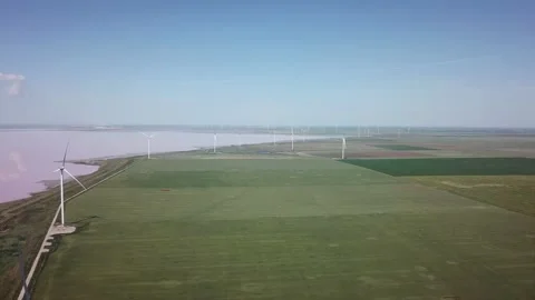 Video of windmills generating electricity and power next to pink salt lake. Stock Footage 208314799
