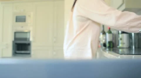 Video of woman going to oven to put a pot inside in kitchen Stock Footage
