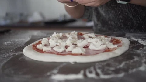 Video of a woman's hand putting some mozzarella on a raw pizza 스톡 동영상 146551883
