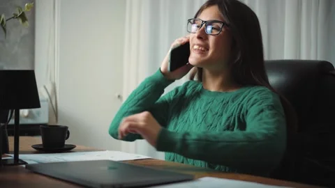 Video of a young Hispanic financial advisor answering a phone call while reviewi Stock Footage 346328960