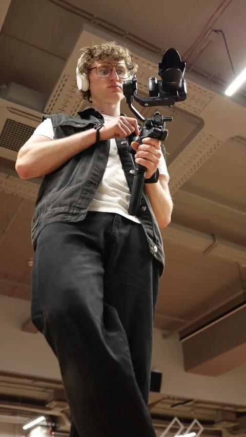 Videographer adjusting stabilizer controls low angle Stock Footage 332116750