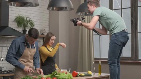 Videographer filming kitchen scene. couple in love preparing healthy meal at Stock Footage 148318500