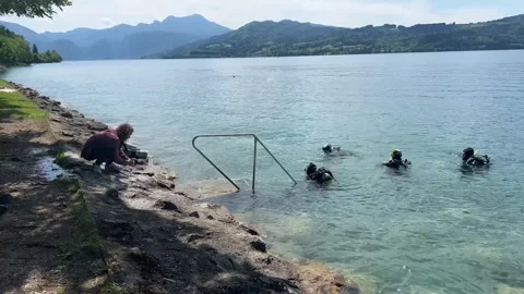 Videographer filming scuba divers during open water training in Lake Attersee Vídeo Stock 330970497