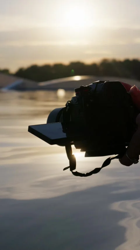 Videographer Holding Mirrorless Camera Above Water at Sunset Close Up Stock Footage 345425179