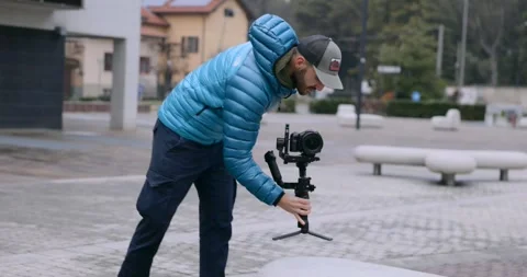 Videographer holding mirrorless camera on gimbal stabilizer 動画素材 339106020