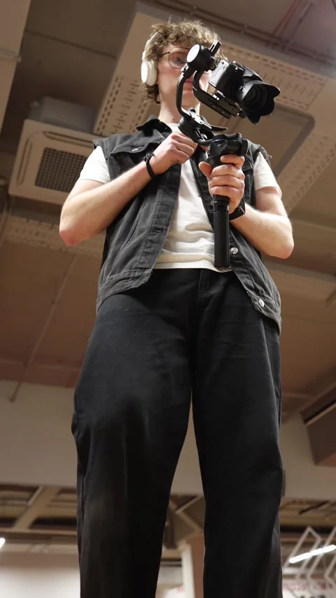 Videographer operating stabilizer camera from low angle Video stock 332116754