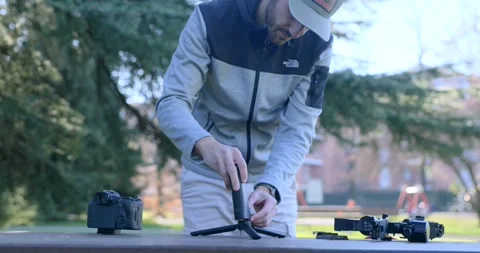 Videographer preparing a mirrorless camera on a DJI RS series gimbal stabilizer Video stock 331972099