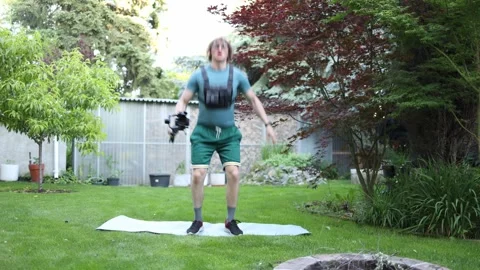 Videographer training endurance with camera and squat jumps Stock Footage 336790693