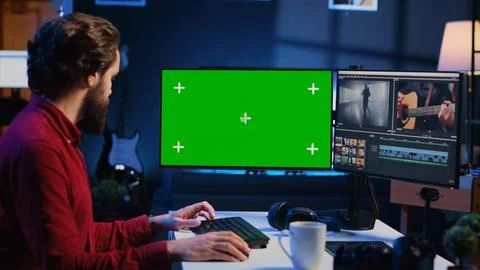 Videographer uses editing software on green screen computer to assemble footage Stock Photos