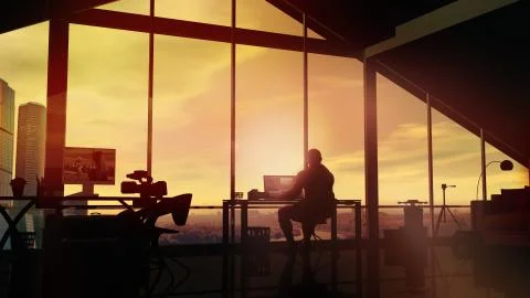 The videographer works at the computer against the background of a sunset Ilustración de archivo