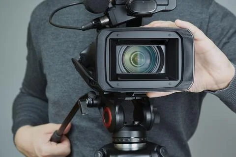 Videographer's hands bring camera into focus, cameraman's work, camcorder wit Stock Photos