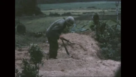 VIETNAM - 1968: Firebase Work - Soldier digs a hillside trench line Stockbeeldmateriaal 343999246