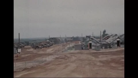 VIETNAM - 1970: Camp overview - Huts and a truck park spread over red earth Stock Footage 344005449