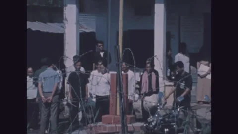 VIETNAM - 1971: Title programme - villagers gather beyond barbed wire 動画素材 343937696