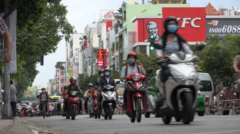 Vietnam, Asia, busy traffic drives past Western KFC fast food chain restaurant Stock Footage