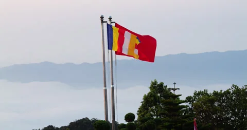 Vietnamese and Buddhist flags waving against a mountain backdrop Stock Footage 345645162