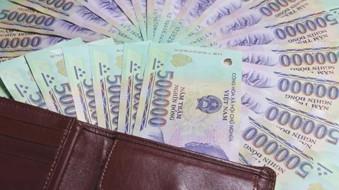 Vietnamese dong banknotes and brown leather wallet on rotating surface Stock Footage 336722896
