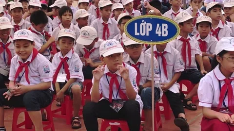 Vietnamese elementary pupils in uniform sit in lines during a school ceremony in Video stock 142180721