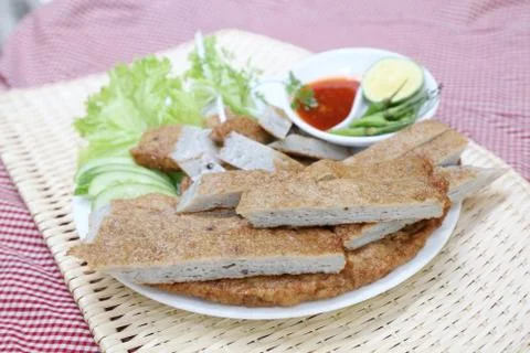 Vietnamese fish paste cake or cha ca on white plate with herbs, cucumber, lem Stock Photos