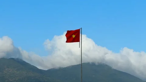 Vietnamese National Flag waving in the wind with mountain covered in clouds Video stock 339045690