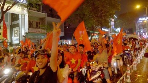 Vietnamese people cheering to the camera waving Vietnamese flags Stock Footage 119862263